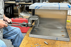 An assembly technician riveting panels on a custom metal enclosure